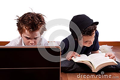 Children playing computer and reading a book Stock Photo