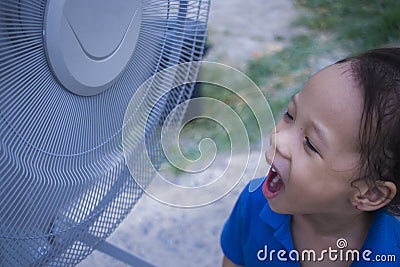 A children playing electric fan and enjoying cool wind in summer season Stock Photo