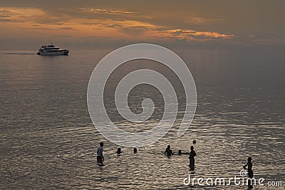 Children playing in the sea as a boat goes past Editorial Stock Photo