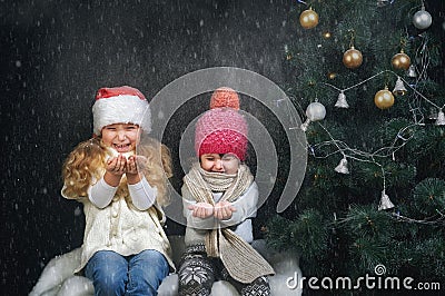 Children playing with snowflakes on dark background near the Christmas tree Stock Photo