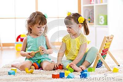 Children playing together with building blocks. Educational toys for preschool and kindergarten kids. Little girls build Stock Photo