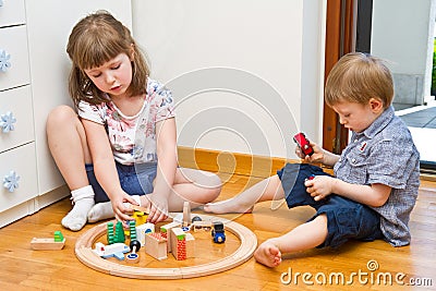 Children playing with wooden train in the room Stock Photo