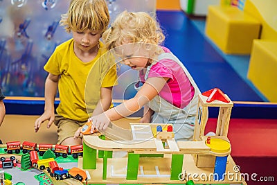Children playing with wooden train. Toddler kid and baby play with blocks, trains and cars. Educational toys for Stock Photo