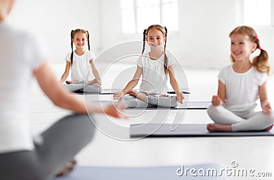 Children practicing yoga in a lotus pose with teacher Stock Photo