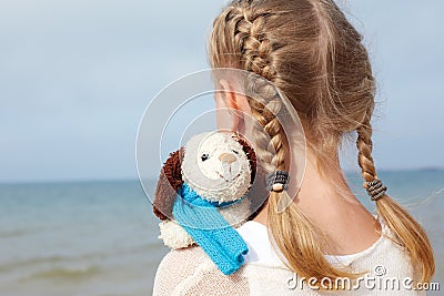 Children psychology. The little beautiful girl embraces an amusing dog - toy. Favorite soft toy. Stock Photo