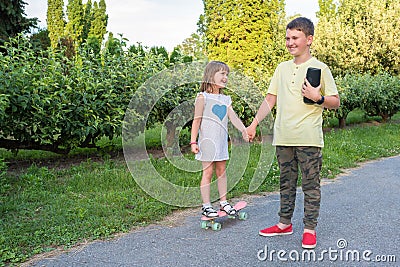 Children ride on a skateboard and listen to music. Outdoor games Stock Photo