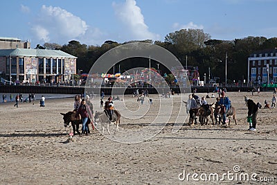 Children riding donkeys on Weymouth Beach in Dorset in the UK Editorial Stock Photo