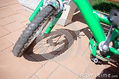 Children`s bicycle wheel and its shadow on the paving stones. Carved shadow from the spokes of a bicycle wheel Stock Photo
