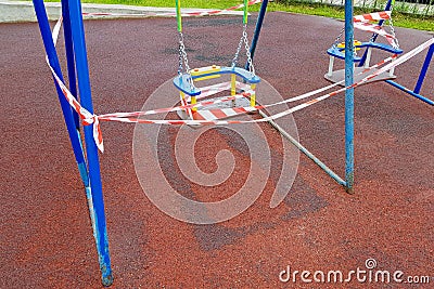 Children's blue swing on a sports playground in the park wrapped with red barrier tape Stock Photo