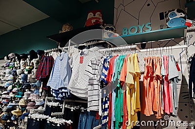 Children`s bright clothes hang on the display in the baby clothing store. Boys section Stock Photo