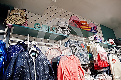 Children`s bright clothes hang on the display in the baby clothing store. Girls section Stock Photo