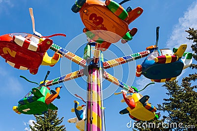 Children`s carousels helicopters in an amusement park, carousels and people during the summer in the city Editorial Stock Photo