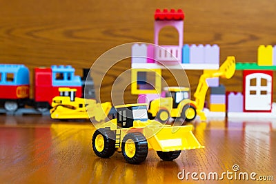 Children`s construction equipment is yellow in the background of a toy building Stock Photo