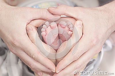 Children`s feet in heartshaped hands of mother and father. Mother, father and Child. Happy Family concept. Beautiful conceptual Stock Photo