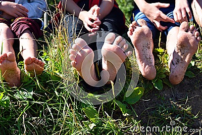 Children`s feet of legs outdoors. Children sit on a grass and show legs Stock Photo