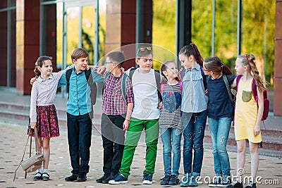 Children`s friendship. Schoolmate students stand in an embrace on the schoolyard. Stock Photo