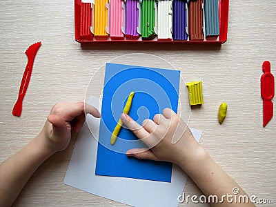 Children's hands with colored plasticine. The child plays and builds figures from play dough. child sculpts from clay Stock Photo