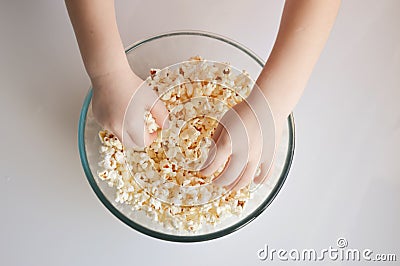 Children`s hands take popcorn in a plate. background for popcorn and movie day decoration. Stock Photo