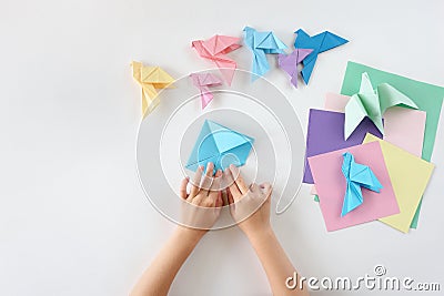 Children`s hands do origami from colored paper on white background. lesson of origami Stock Photo