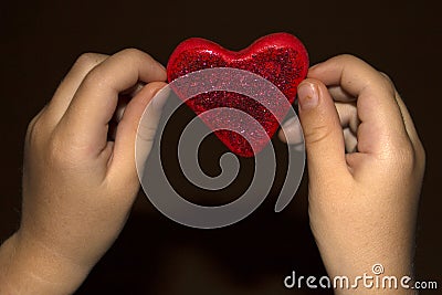 Children`s hands hold plasticine heart. Stock Photo