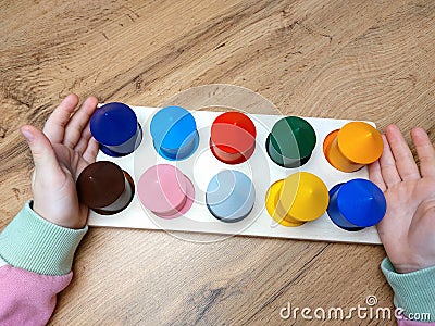 Children's hands hold a tablet with colorful wooden houses. Montessori method. Stock Photo