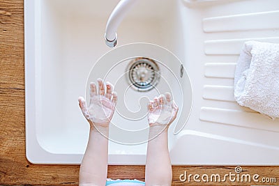 Children's hands in soapy foam over a light sink. View from above. Hygiene and healthcare concept Stock Photo