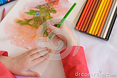 Children`s hands on a white table drawing Christmas tree with olorecd pencils. Drawing a Christmas tree with pencils Stock Photo