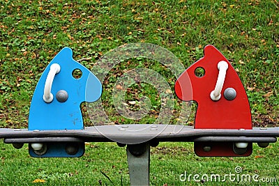 Children's play area with seesaw for children to play in the open air. Red and blue horse version with handles. To balance. Editorial Stock Photo