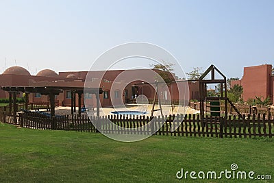 Children`s pool with sand, swings, slide, round pool and wooden pergola. Well-kept tropical garden with English lawn, colorful Stock Photo