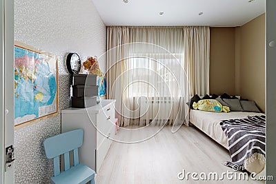 A children's room with a pink and blue chair, a window and a map on the wall Stock Photo