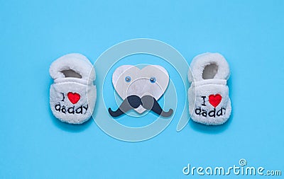 Children`s shoes and a heart with a mustache on blue. Stock Photo