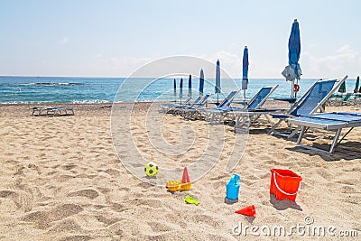 children& x27;s toys on the beach sand against turquoise sea Stock Photo