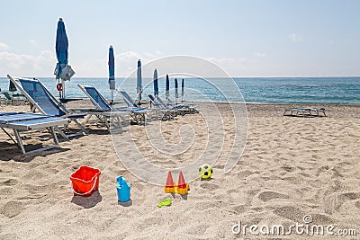 children& x27;s toys on the beach sand against turquoise sea Stock Photo