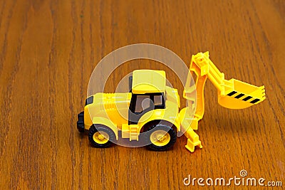 Children`s tractor yellow on a brown background Stock Photo