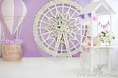 Children`s, wedding, festive photo zone. Trolley with lollipops, cake, cupcakes, balloon with basket, flower arch wheel. Copy Stock Photo