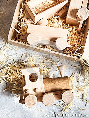Children`s wooden toys. Children wooden train with wagons in the box with sawdust. Natural wood construction set Stock Photo