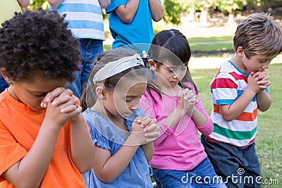 Children saying their prayers in park Stock Photo