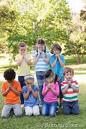 Children saying their prayers in park Stock Photo