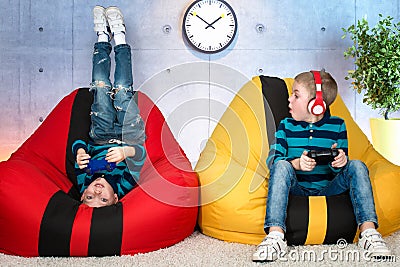 Children sit on chairs bags and play video games .Children`s emotions. Stock Photo