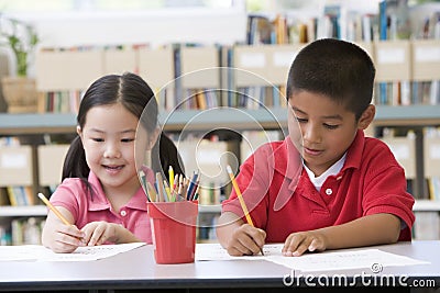 Children sitting at desk and writing in classroom Stock Photo