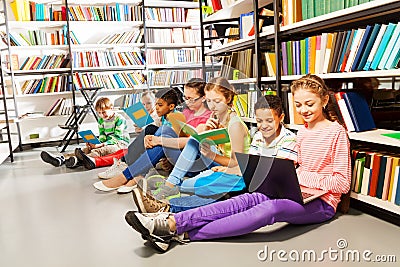 Children sitting on floor in library and studying Stock Photo