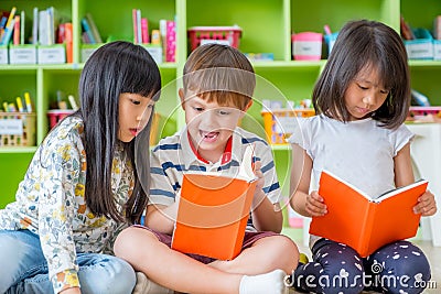 Children sitting on floor and reading tale book in preschool li Stock Photo