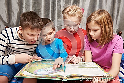 Children sitting and reading geography book Stock Photo