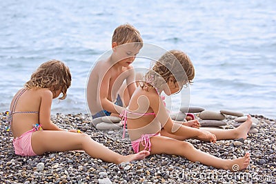 Children sitting on stony beach, creates pyramid Stock Photo