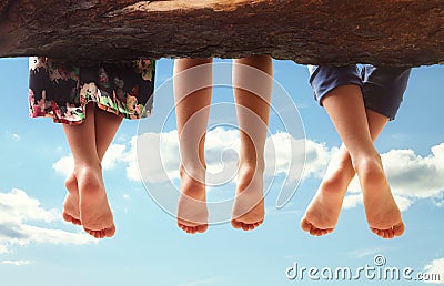 Children sitting in a tree dangling their feet Stock Photo