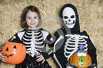 Children In Skeleton Costumes Holding Jack-O-Lanterns Stock Photo