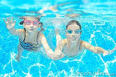 Children swim in pool under water, happy active girls in goggles have fun, kids sport Stock Photo