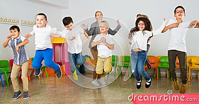 Children with teacher jumping together in schoolroom Stock Photo