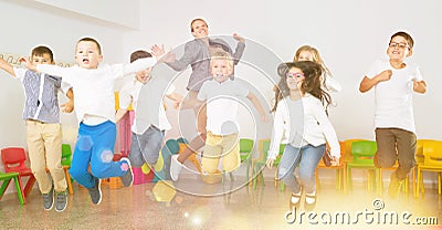 Children with teacher jumping together in schoolroom Stock Photo