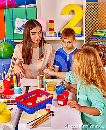 Children with teacher woman painting on paper in kindergarten . Stock Photo